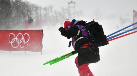 A volunteer skis past a barrier bearing the Olympic rings as the start of the slalom course Wednesday. (Getty Images/AFP – Fabrice Coffrini)