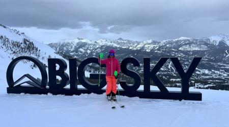 Vera Savage with Big Sky written out behind her in 4ft tall letters and a beautiful mountain view.